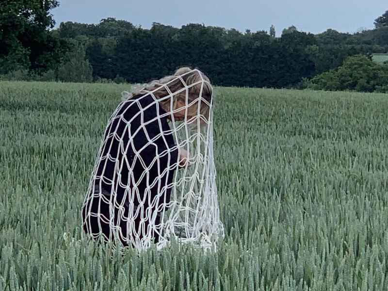 Image of a woman in a net in a field, work in progress, Annabel Pettigrew, 2021